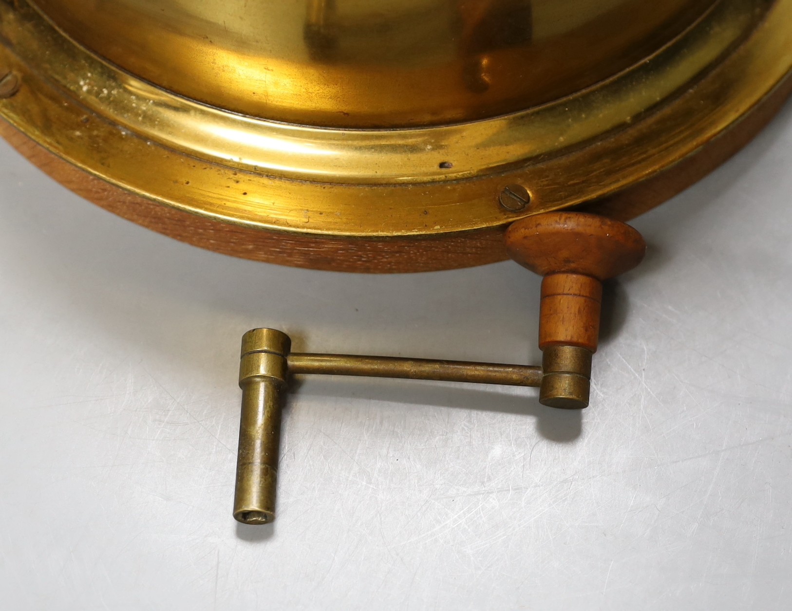A brass ship’s bulkhead timepiece with key